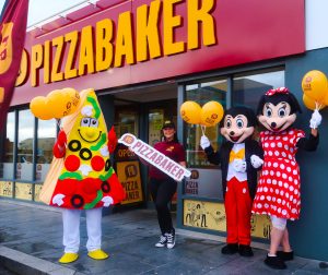 Pizzabaker Belfast located on Andersonstown Road celebrates first birthday with pizza macot, Micky and Minnie Mouse mascot holding balloons outside of Pizzabaker Andersonstown Road store